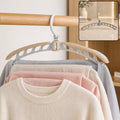 A beige and white folding hanger holding a cream sweater and light colored pants on a wooden rail. Inset shows the hanger