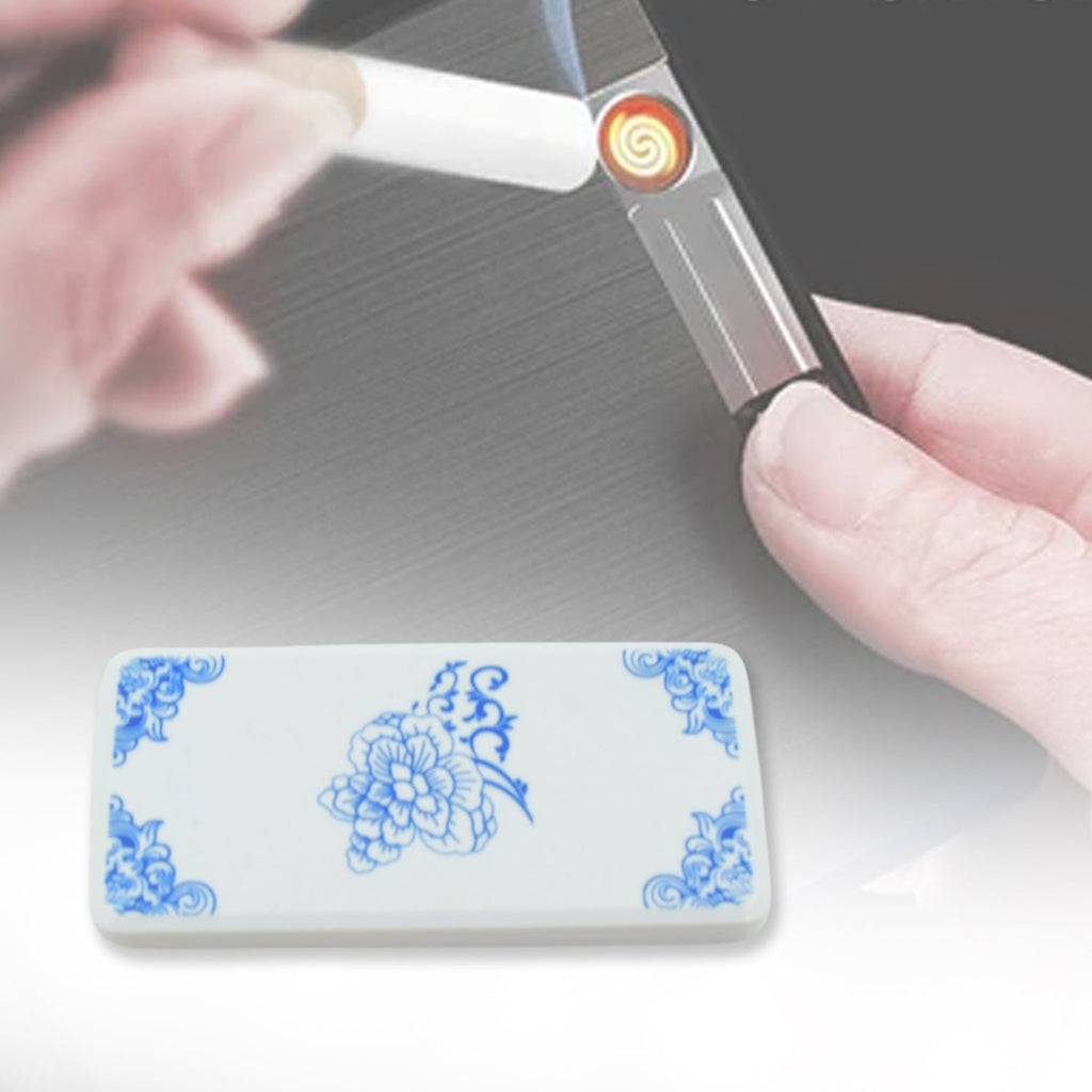 A white rectangular lighter with blue floral corners and center, next to a hand holding a different lighter.