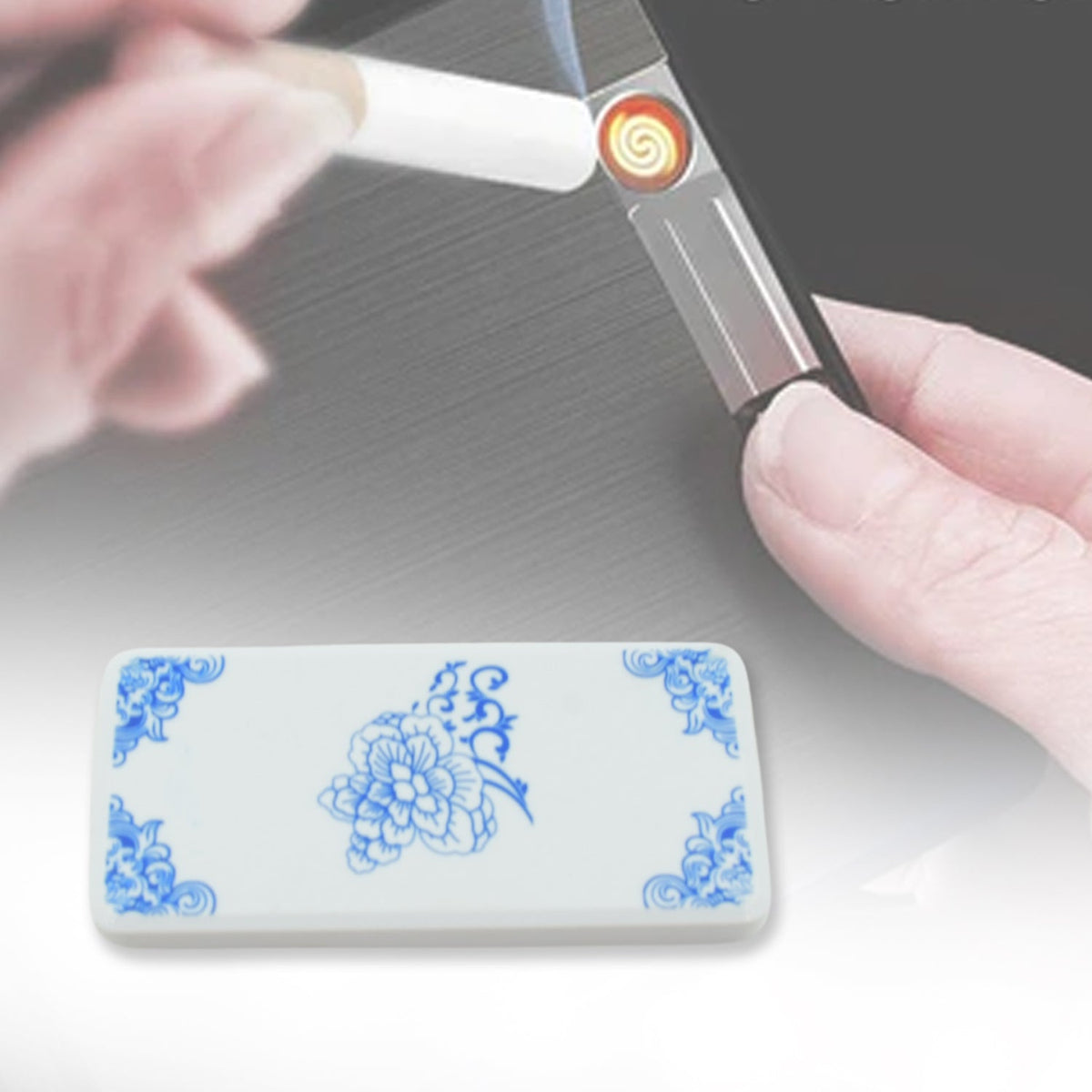 A white rectangular lighter with blue floral corners and center, next to a hand holding a different lighter.
