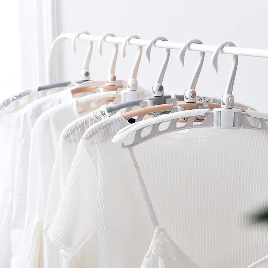A row of white, beige, and gray folding hangers holding white shirts on a white clothing rack.