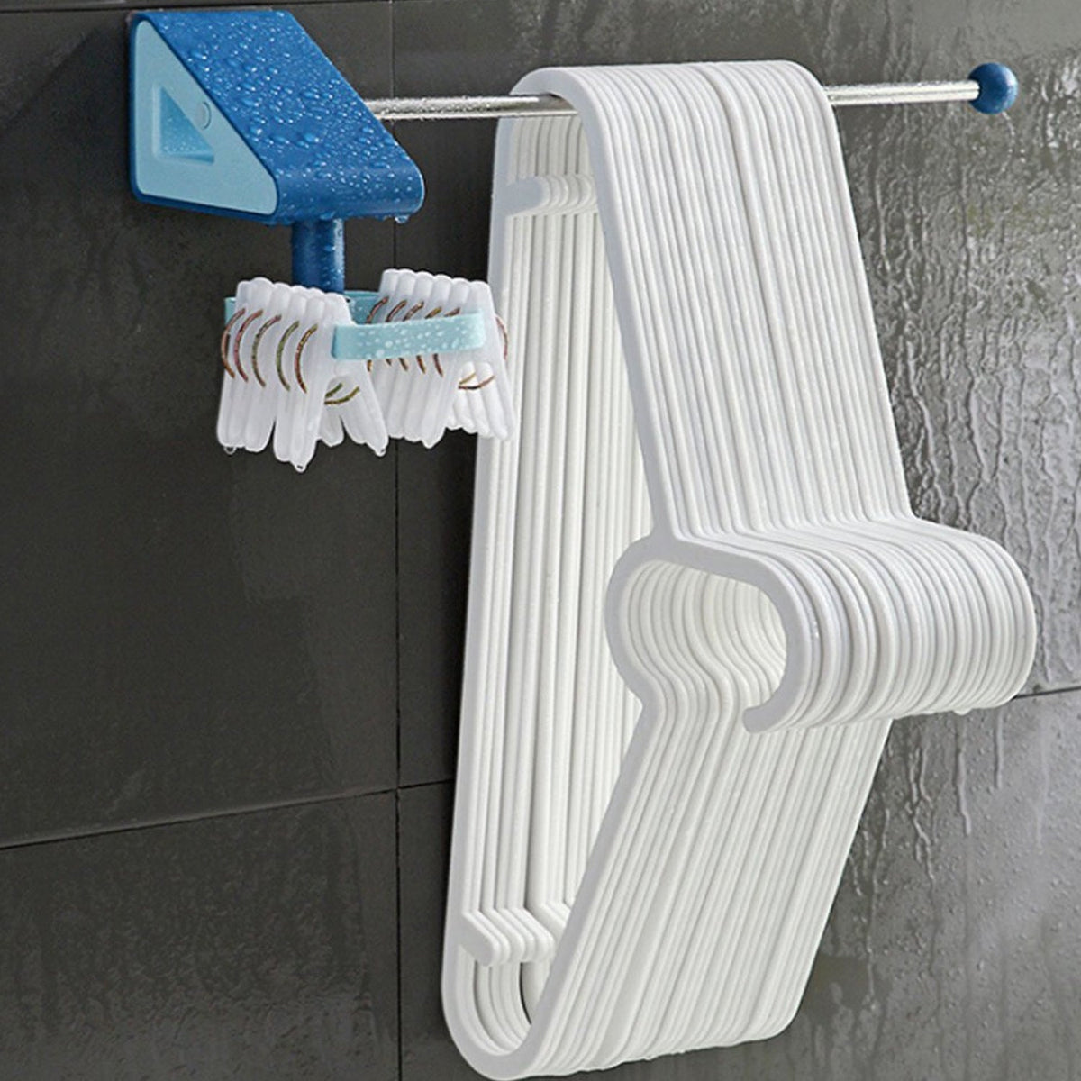 Blue and light blue wall-mounted drying rack with a silver rod holding multiple white plastic clothes hangers and small
