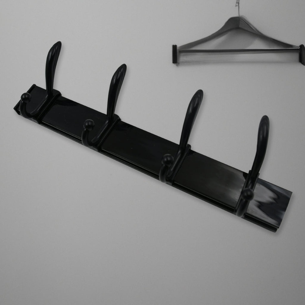 Black four-hook coat rack mounted on a light wall, with a dark wooden clothes hanger visible above it.