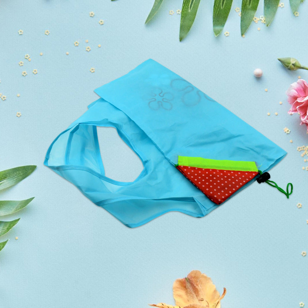 A light blue reusable shopping bag with flower designs is folded on a blue surface with green leaves and pink flowers.