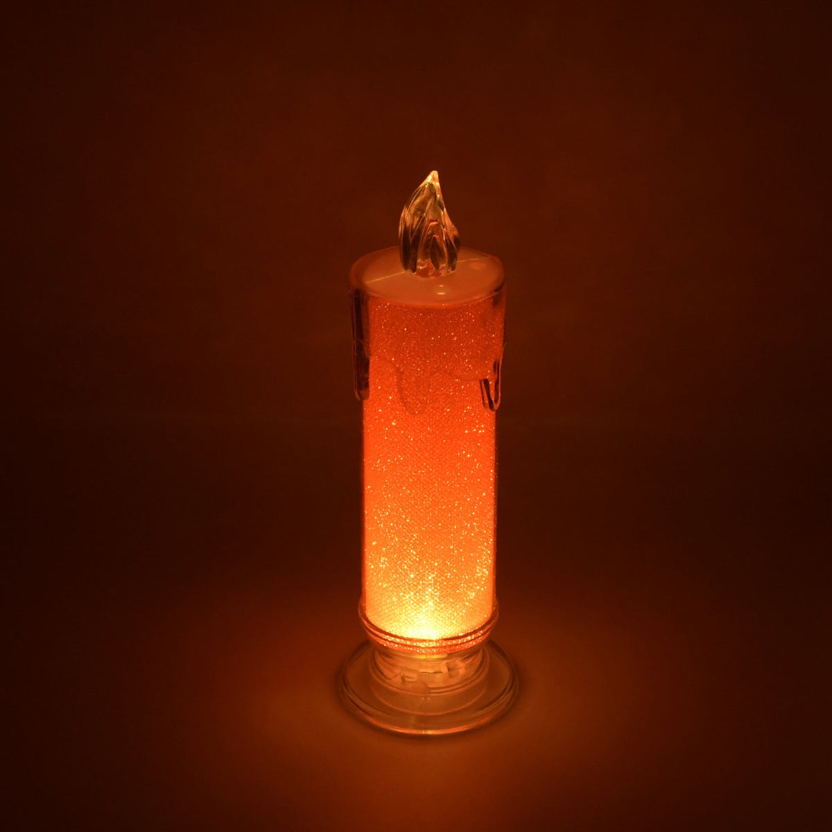 A glowing red LED candle with glitter inside, featuring a clear plastic base and a flame-shaped top.