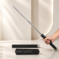 A hand holds an extended silver metal baton with a black foam grip, with a collapsed baton and black carrying case on a