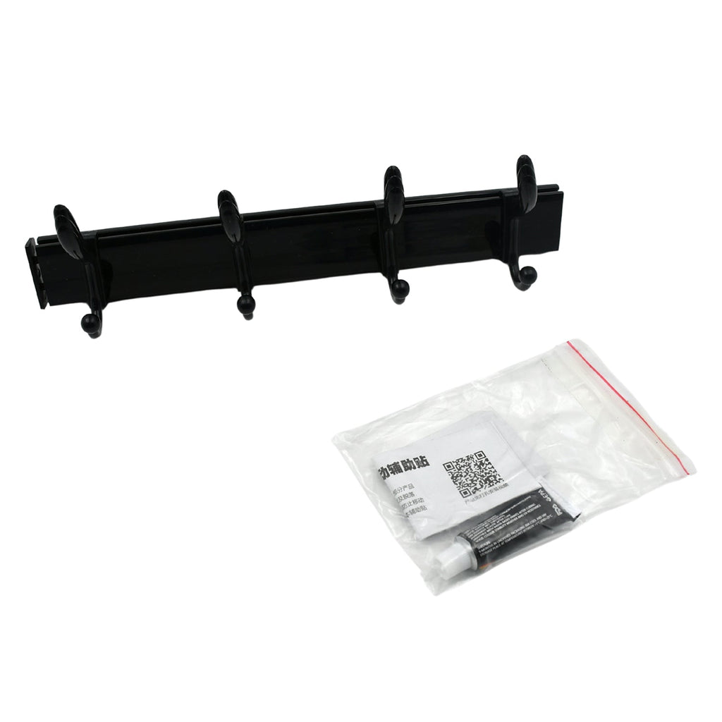 Black four-hook coat rack and a clear plastic bag containing adhesive and instructions on a white background.