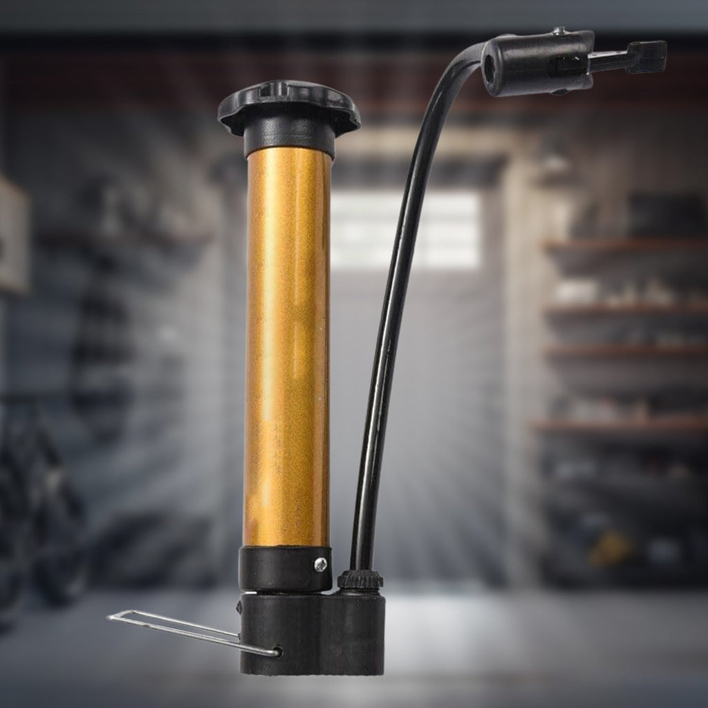 A gold and black hand pump with a black hose and nozzle stands in a garage setting.