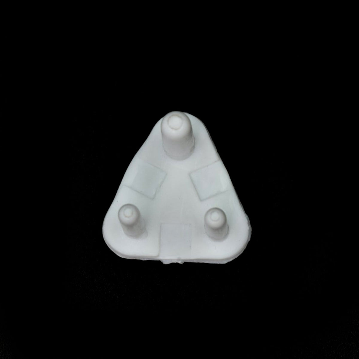 A single white plastic child safety socket cover, triangular with three prongs, viewed from directly above on a black