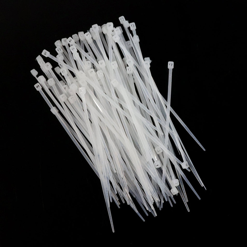 A large pile of white nylon cable ties scattered on a black background.