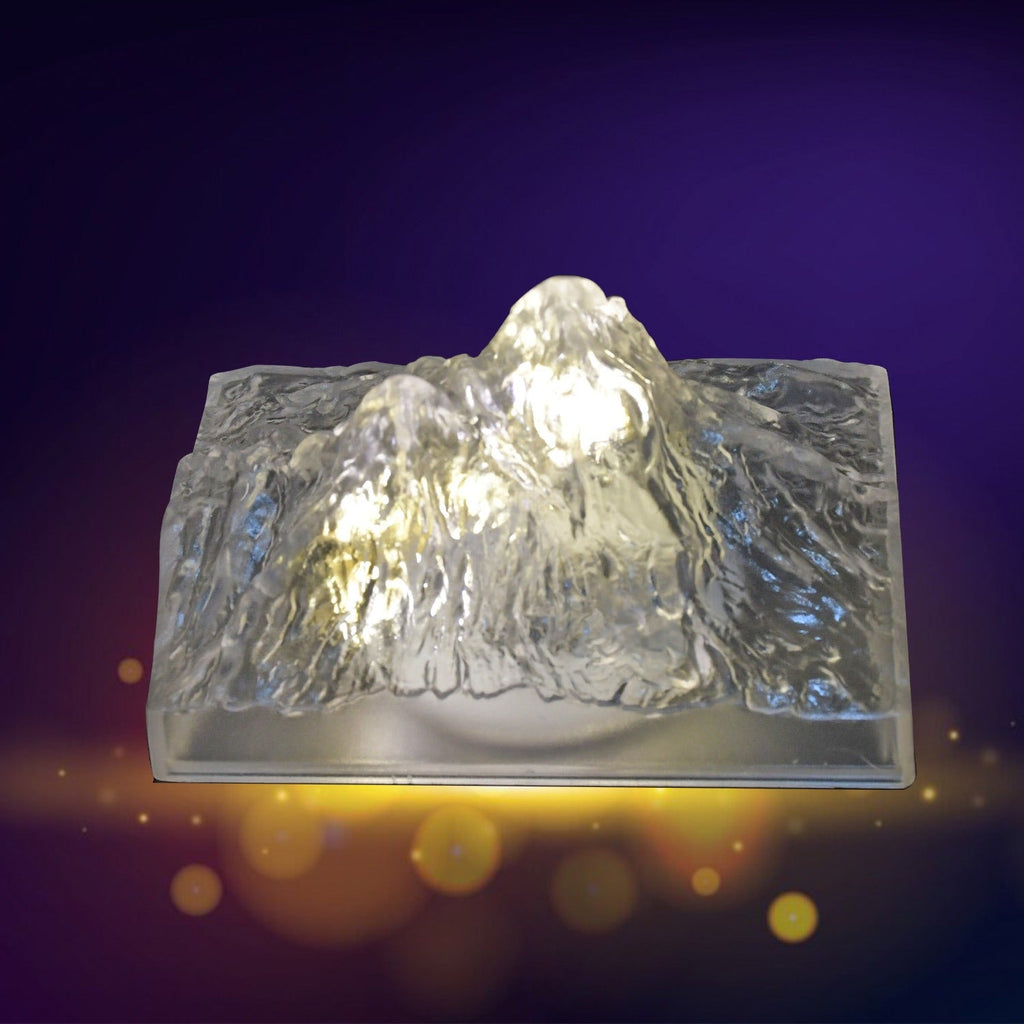 A clear, textured iceberg-shaped LED light glows warmly on a purple background with golden bokeh lights.