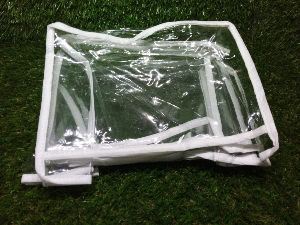 A clear plastic and white fabric organizer, folded flat, rests on a textured green surface.
