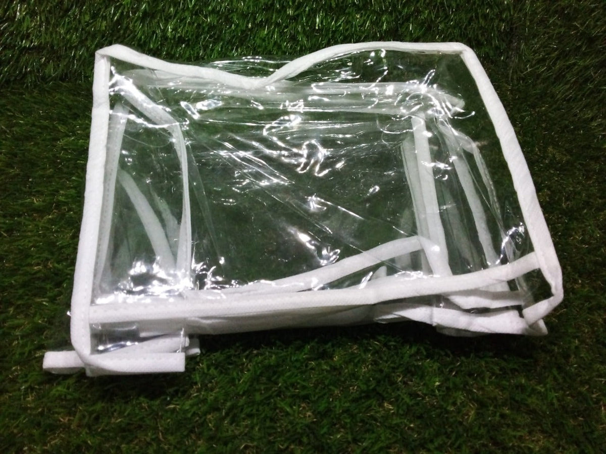 A clear plastic and white fabric organizer, folded flat, rests on a textured green surface.