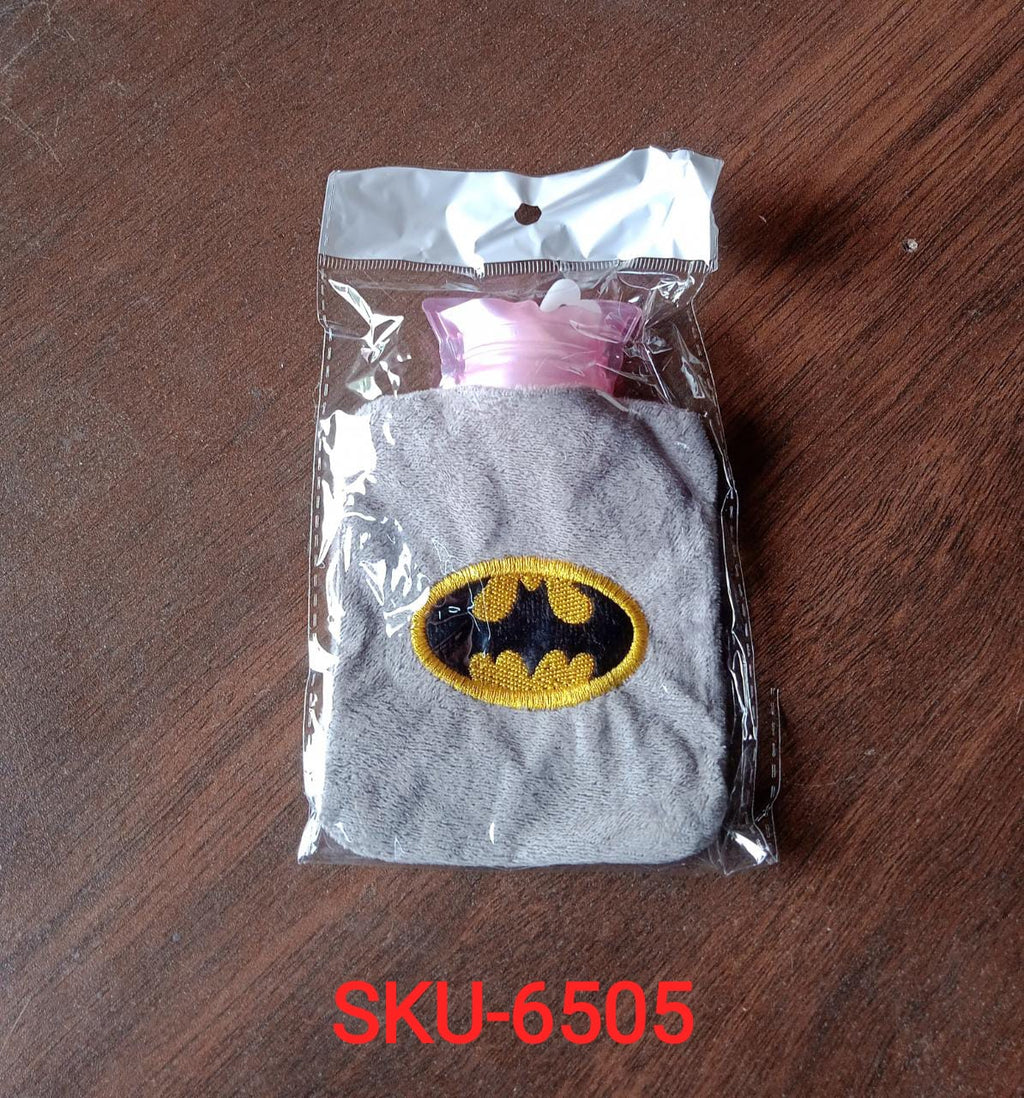 Gray plush hot water bag with a Batman logo in clear plastic packaging on a dark brown surface.