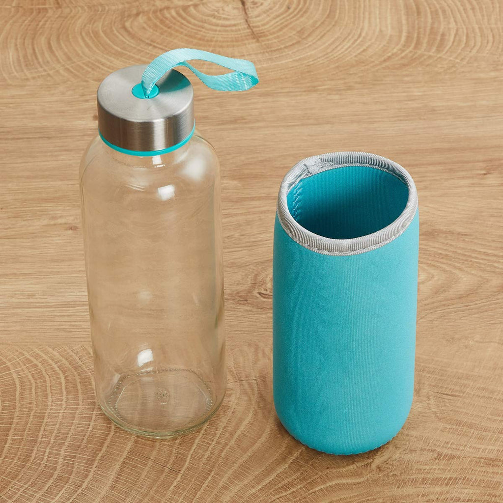 A clear glass bottle with a silver lid and a separate turquoise sleeve are placed on a wooden surface.