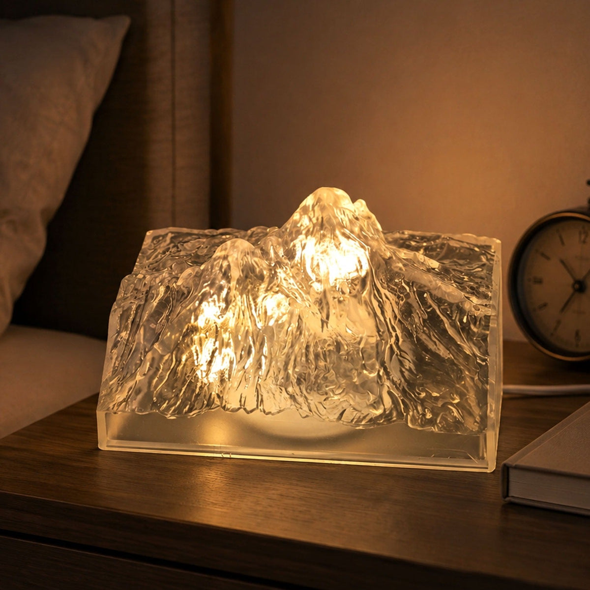 A clear, textured iceberg-shaped LED light glows warmly on a wooden bedside table next to a pillow.