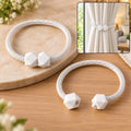 Two white braided rope curtain tiebacks with geometric white plastic fasteners, one shown in use on a curtain.