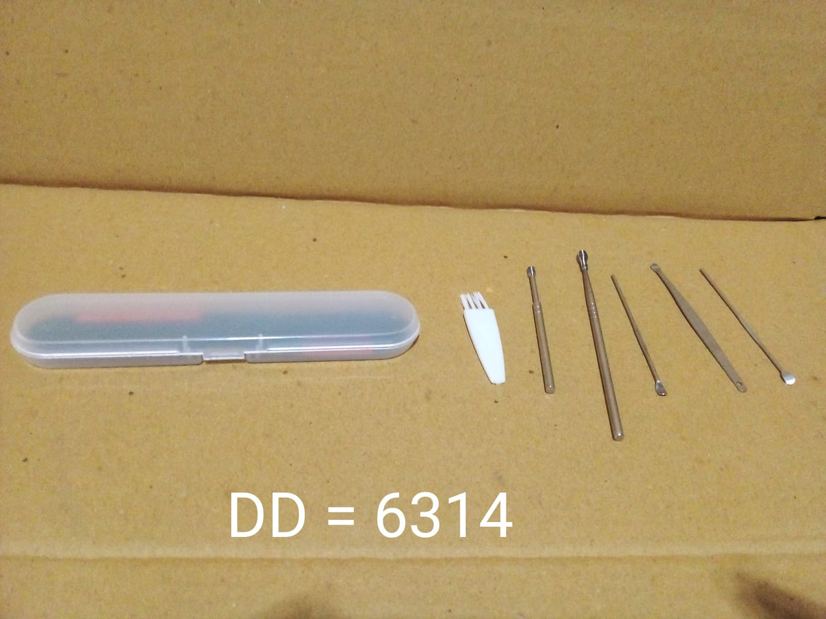 The 6-piece silver ear cleaning kit with its clear case and white brush laid out on a cardboard surface.